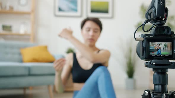 Closeup of Camera Screen and Young Woman Exercising Doing Yoga in Background alt