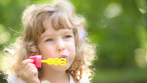 Happy Child Playing With Soap Bubbles