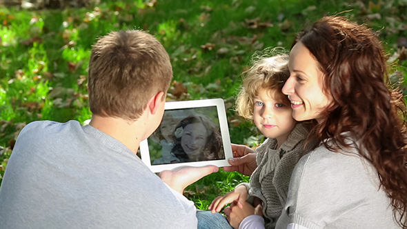 Family Using Tablet PC In Autumn Park