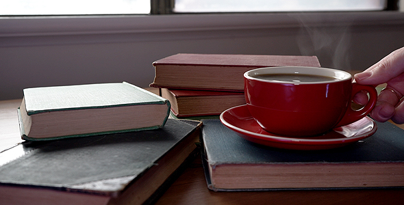 Steaming Cup Of Black Coffee On Old Books