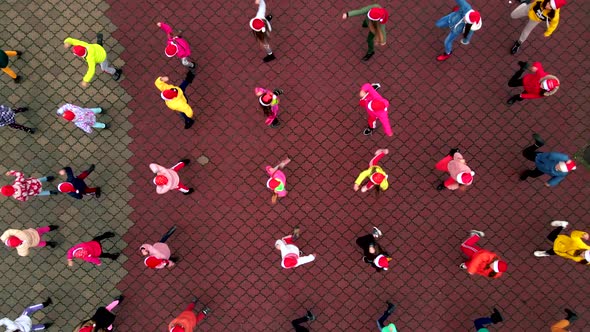 Happy children with Santa Christmas hats dancing on the square. Top down aerial view, 4k footage alt