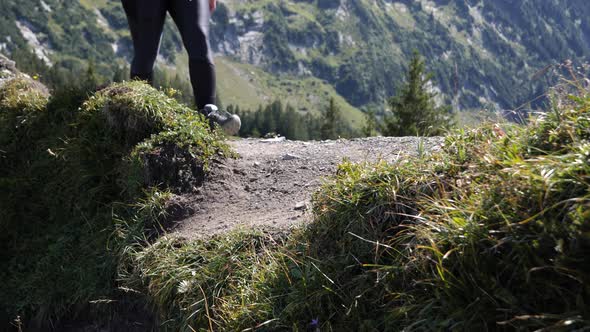 Female person hiking on dangerous edge trail in swiss alps during sunny day.Slow motion low angle sh alt