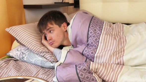 Young Man Waking Up In Bedroom alt
