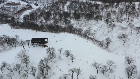 people skiing past a chair lift on a snow slope in nozwa onsen ski resort in nagano japan, aerial alt