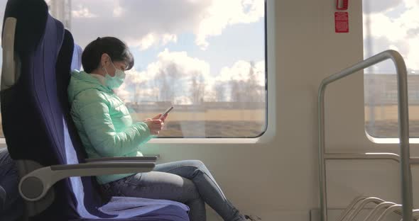 Woman Wearing a Protective Medical Face Mask Rides on a Train During the Covid 19 Quarantine alt