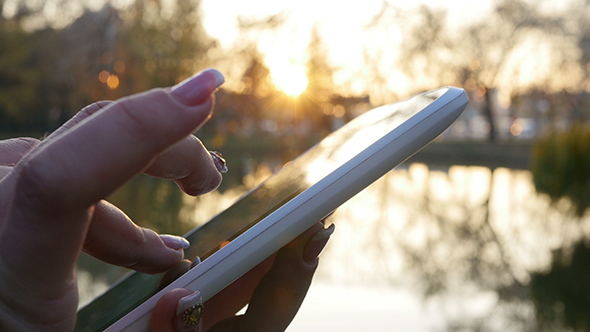 Woman Using Her Touchpad Near Lake in Sunset