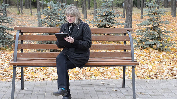 A Woman on a Bench With the Tablet