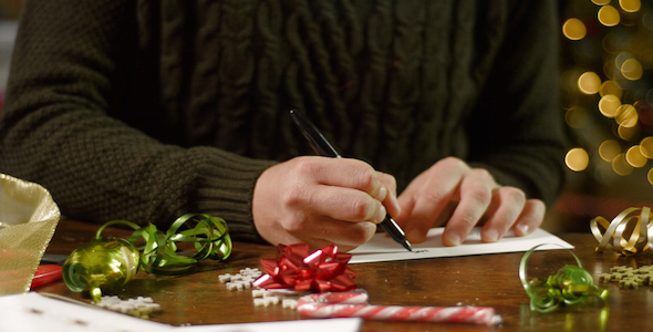 Man Writes a Card with Candy Canes in Foreground