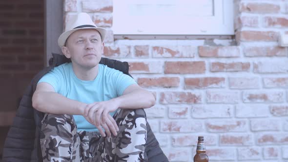 Man in Hat is Resting While Sitting on the Porch of His House Vacation Concept alt