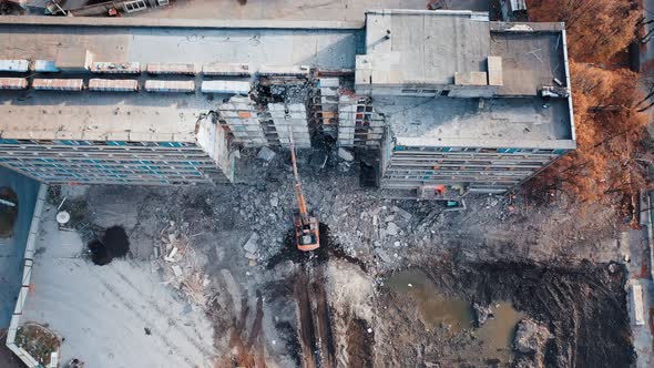 A demolition excavator destroys an old unusable building. alt