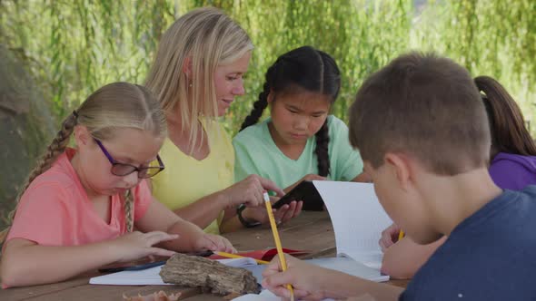 Kids at outdoor school writing in notebooks