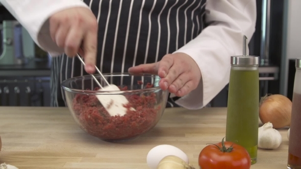 Chef Mixing Meat In a Glass Bowl In The Kitchen