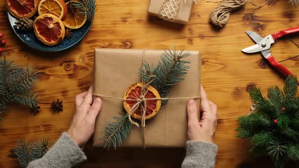 Woman Puts Christmas Present on Table alt