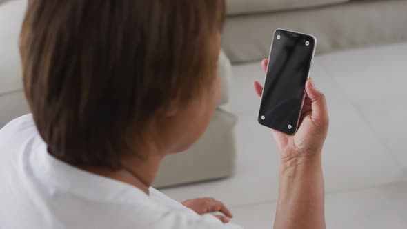 African american senior woman sitting on couch using smartphone, with copy space on screen alt
