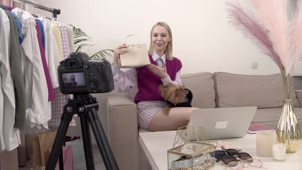 A Blonde Female Stylist Smiles and Shows Her Small Bag to the Camera