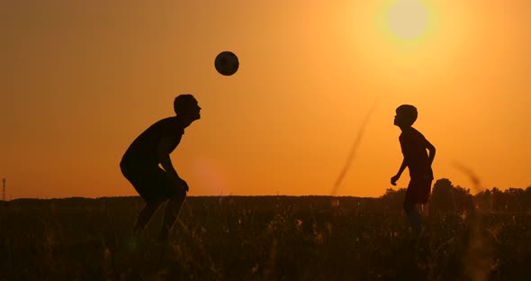 Father and Son Playing Football in the Park at Sunset, Silhouettes Against  the Backdrop of a Bright, Stock Footage