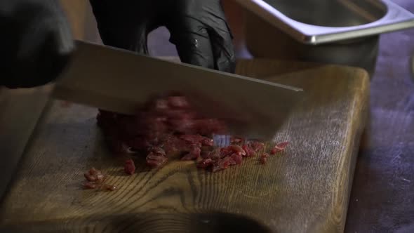 Cook Cuts Raw Meat on a Wooden Board