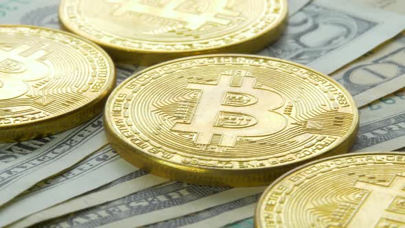 Golden Shiny Bitcoin Coins Rotating on Bills of Dollars Bill