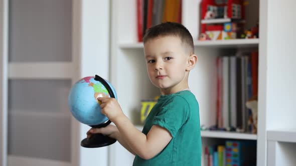 Little boy with a globe in his hands shows thumb up alt