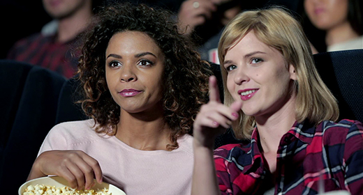 Cinema, entertainment and people concept - happy friends watching movie in theater