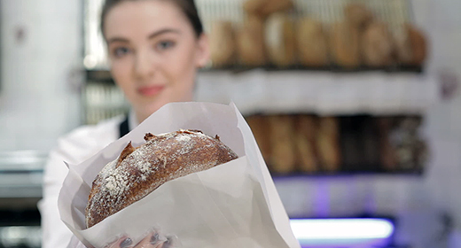 Young smiling baker inside the coffee shop or bakery