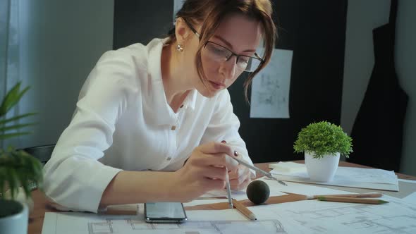 Young pretty engineer, architect or designer woman works with drawings in office