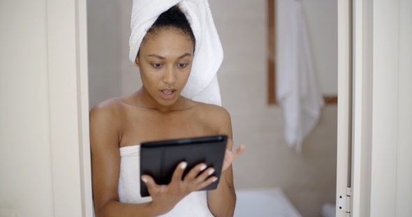 Woman Wearing Bath Towel Using Tablet Computer alt