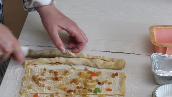 A Woman Cuts A Roll Of Rolled Dough. Prepares Cruffin With Raisins And Candied Fruit. alt