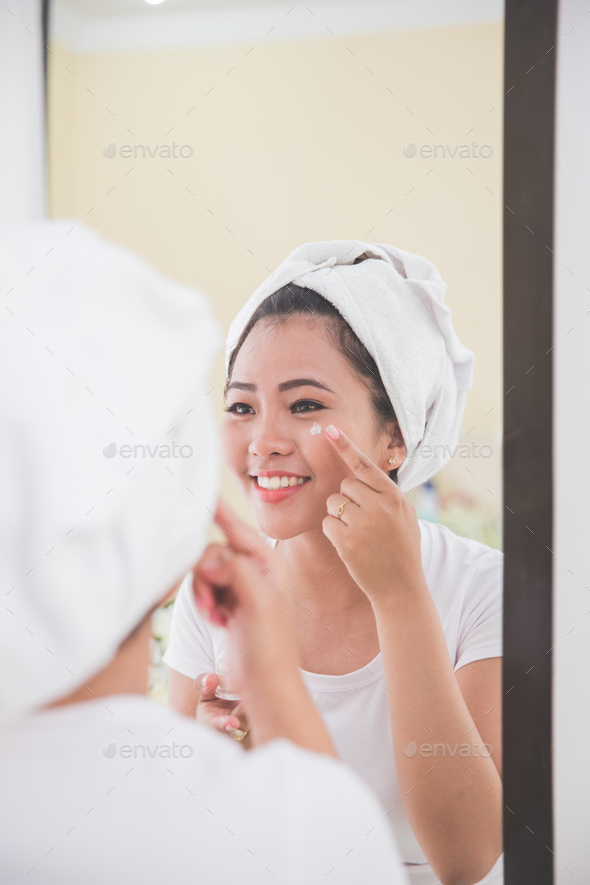 Woman applying skincare lotion into her face