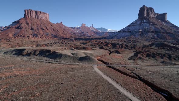 Flying over dirt road towards Castleton Tower past mesas alt