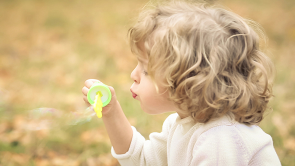 Child Blowing Soap Bubbles In Autumn Park