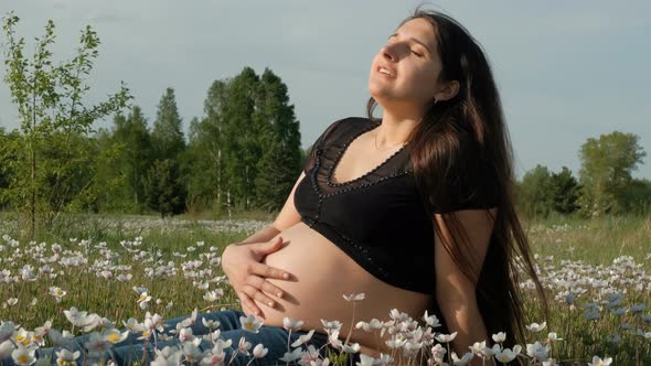 Young Pregnant Woman Sitting in a Flower Field