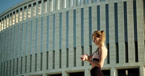 Athletic Girl Looks at Smart Watch