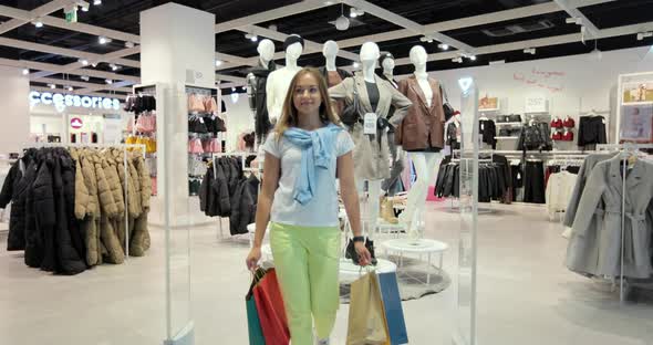 Young Woman Jumping for Joy with Colorful Bags in Hands After Successful Shopping at Store alt