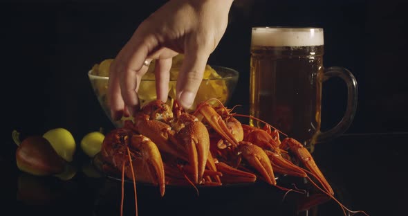 Close Up View of Man Arm Taking Lobsters with Foamy Bear Pouring in Glass and Crisp Chips on