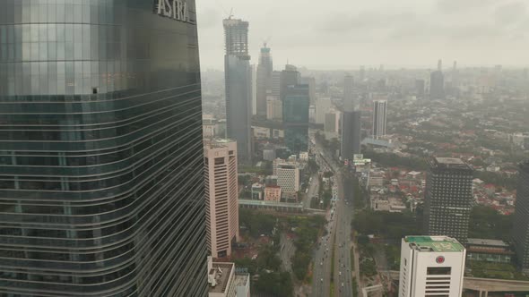Aerial View Reveal Flying From Behind a Skyscraper To Wide View of Jakarta City Skyline Reveal  alt