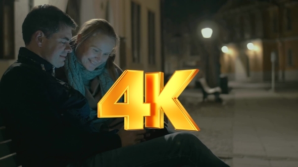 Young Couple Using Pad On The Street Bench alt