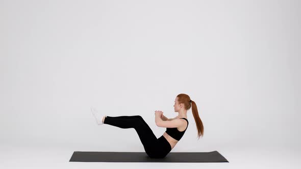 Sporty Young Female Making Feet Elevated Oblique Crunch Exercise In Studio alt
