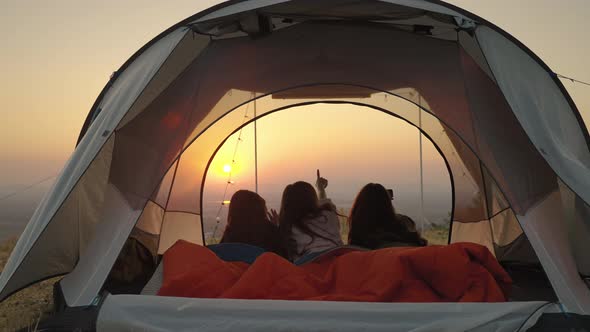 girl friend group Asians laying in tents during camping are waking up to watch the sun rise