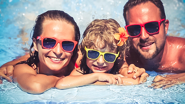 Happy Family Having Fun In Swimming Pool