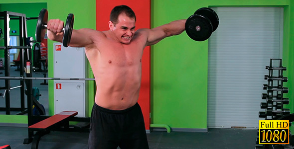 A Man Raises His Arms With Dumbbells