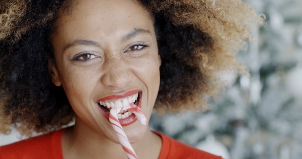 Fun Young Woman Biting Christmas Candy Cane alt