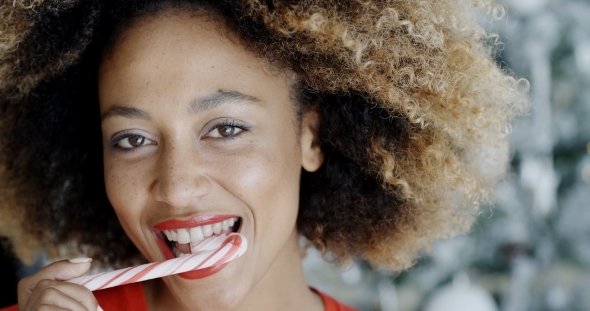 Young Woman Biting a Festive Candy Cane alt