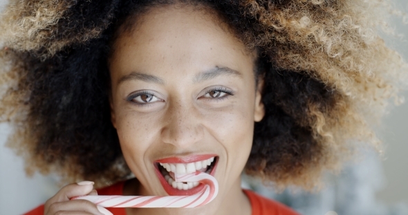 Young Woman Biting a Festive Candy Cane alt