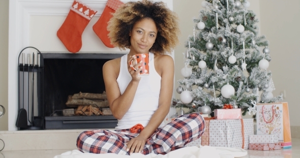 Smiling Young Woman Enjoying a Cup Of Xmas Coffee alt