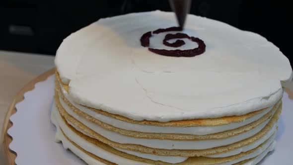 Pastry Chef Prepares a Sponge Cake with Cream and Jam Filled with Many Layers alt