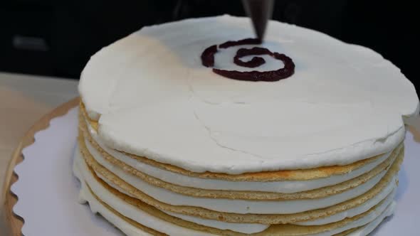 Pastry Chef Prepares a Sponge Cake with Cream and Jam Filled with Many Layers