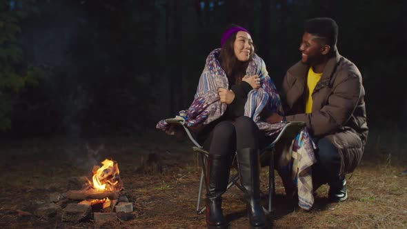 Man Covering Cold Woman with Blanket in Camping alt