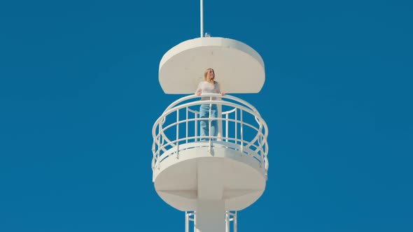 Girl in Beach Lifeguard Tower on Isolated Blue Sky alt