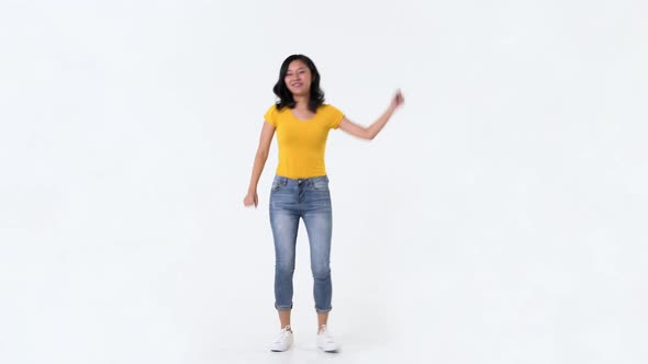 Happy young Asian woman in yellow t-shirt dancing in studio white background